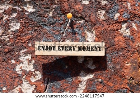 ENJOY EVERY MOMENT is written on the wooden surface. Wooden Concept.