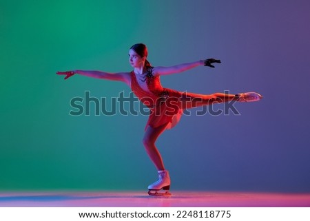 Young sportive girl, junior female figure skater in red stage costume skating isolated over gradient green-blue background in neon. Athlete in motion. Sport, beauty, winter sports. Copy space for ad
