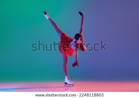 Young sportive girl, junior female figure skater in red stage costume skating isolated over gradient green-blue background in neon. Athlete in motion. Sport, beauty, winter sports. Copy space for ad