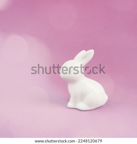 Easter bunny or rabbit sitting on a pink pastel colored background, spring holiday greeting card, bokeh light 