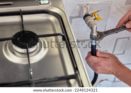 Gasman disconnects flexible hose from gas stove. Royalty-Free Stock Photo #2248124321