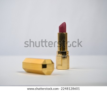 Lipstick with golden colored tube over white background. 