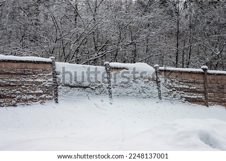 a partly damaged fence after snowfall, winter scene, no people 