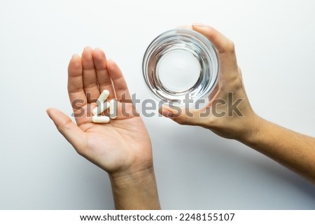 Hands holding pills and a glass of water, supplementation and health, vitamin replenishment concept Royalty-Free Stock Photo #2248155107