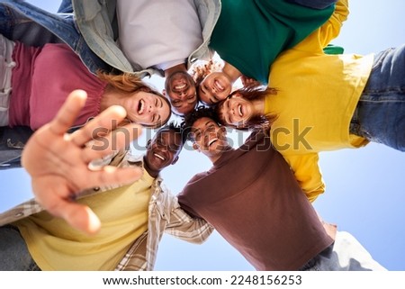 Internacional Erasmus students looking at camera cheerfully embracing each other. Group of people in circle looking down. Low angle view. Copy space.