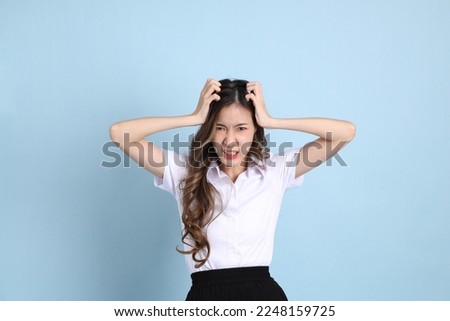 The young Asian student with uniform standing on the blue background. Royalty-Free Stock Photo #2248159725