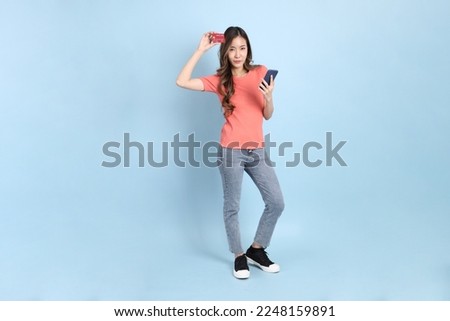 The young adult Asian woman with casual clothes with jeans standing on the blue background.