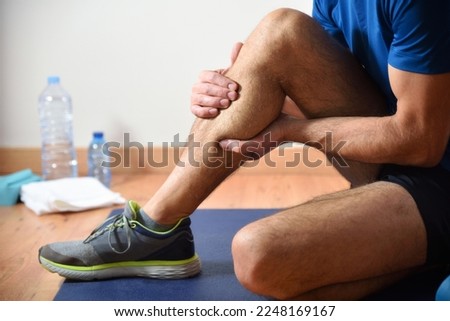 Detail of man doing sports with calf pain holding himself with his hand sitting on a mat. Side view.
 Royalty-Free Stock Photo #2248169167