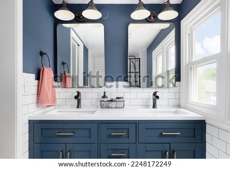 Styled Home Still Lifestyle Image. Contemporary Dark Blue Bathroom with Double Vanity, Modern Mirrors, and White Subway Tile Backsplash. Royalty-Free Stock Photo #2248172249
