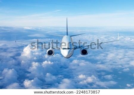 Passenger civil airplane jet flying at flight level high in the sky above the clouds and blue sky. View directly in front, exactly Royalty-Free Stock Photo #2248173857