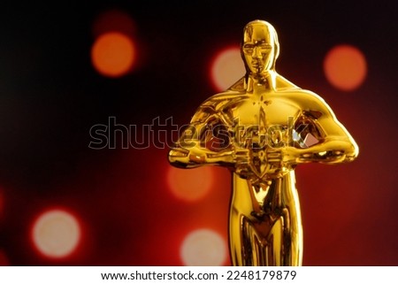Hollywood Golden Oscar Academy award statue on blue background with light rays. Success and victory concept.