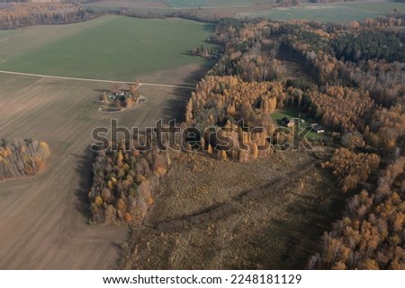  an aerial view of a farm surrounded by trees and fields with a house in the middle of the picture, surrounded by trees with yellow and orange leaves, and green grass, and brown. . 