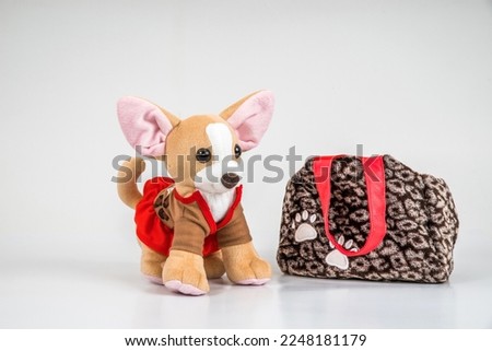 A handbag and a soft children's toy dog in a red dress on a white background.