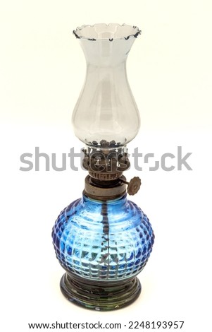 Blue colored glass oil lamp with old weathered and rusted glass. Close-up, on a white background. Royalty-Free Stock Photo #2248193957