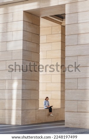 woman is resting after work, modern architecture, beige columns in business center or office building. urban. full-length photo.
