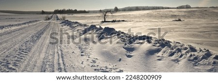 Winter road. Winter landscape of road. Snowy winter on the countryside, black and white picture. Highway leading through snowy fields. Drifts on the road.
Snowy road  of panoramic landscape.