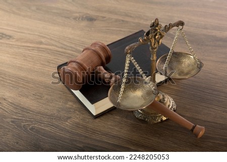 Scales, judge's gavel and a book of judicial laws on a wooden table