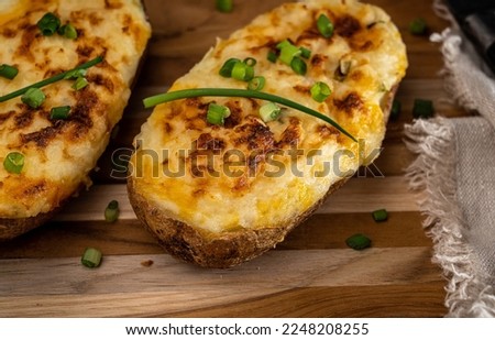 Cheesy twice-baked potato garnished with chopped scallion. Royalty-Free Stock Photo #2248208255
