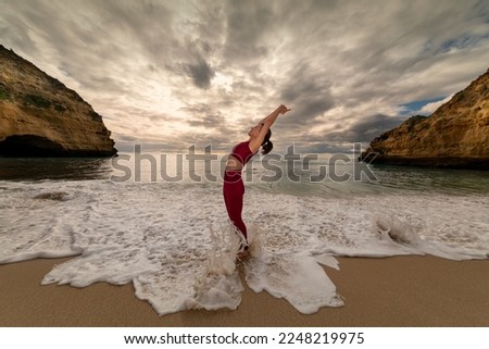 yoga girl doing a backbend by the sea with a dramatic sky.