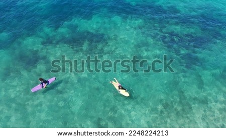 Aerial drone top down photo of surfers having surfing lesson in tropical exotic wavy bay with deep emerald sea