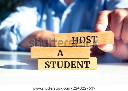 Closeup on businessman holding a wooden block with "Host a Student" message