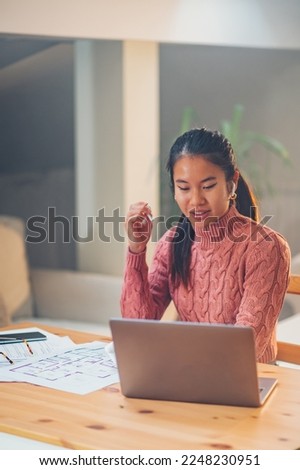 Portrait of a beautiful asian woman using laptop while sitting at the table at home. Young creative Vietnamese female typing on a keyboard while working remotely. Working at home concept. Copy space.
