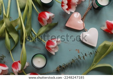 Red tulips, hearts and candles on a wooden table. Valentines, mothers, womens day, wedding or birthday flat lay concept. Top view.