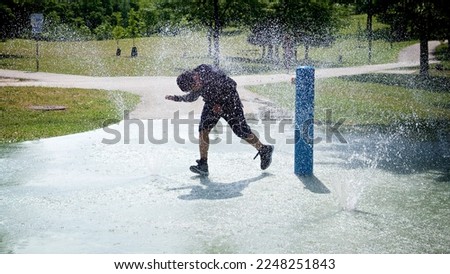 In a hot summer day, a boy running between the sprinkler. Outdoor fun. 