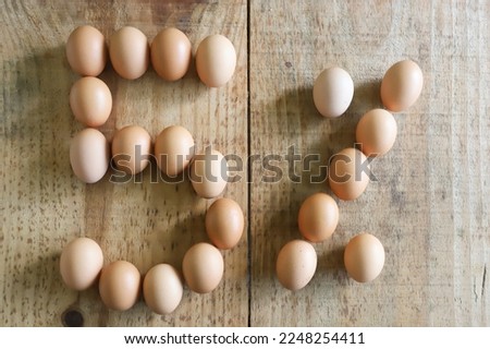 5% numeral written with chicken eggs arranged on a rustic pine wood base.