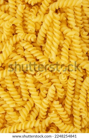 Raw dry fusilli pasta, food background texture, top view