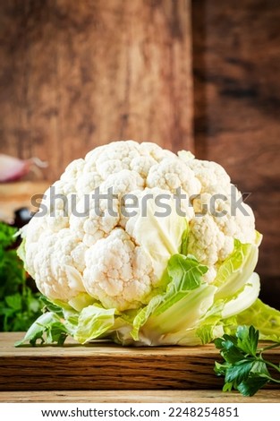 Food background with organic farm cauliflower, pumpkins, herbs and spices on rustic wood kitchen table with spice grinders, herbs and cutting board