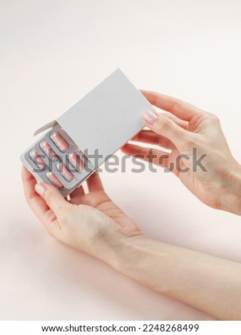 Blank White Product Package Box Mock-up in a female hand. Open blank medicine drug box with Vatamin a blister top view. Place for logo and text Royalty-Free Stock Photo #2248268499