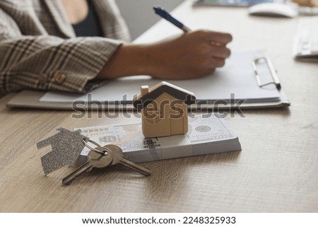 Real estate agent working sign agreement document contract for home loan insurance approving purchases for client with house model money and key on table