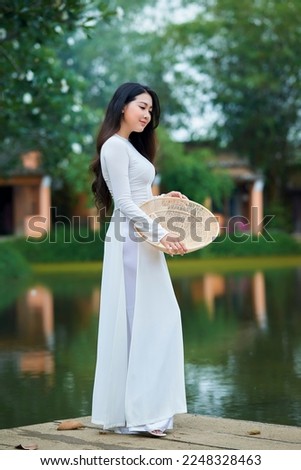 Ho Chi Minh city, Viet Nam: Ao Dai is traditional dress of vietnam, beautiful vietnamese woman in white Ao Dai dress in the park Royalty-Free Stock Photo #2248328463