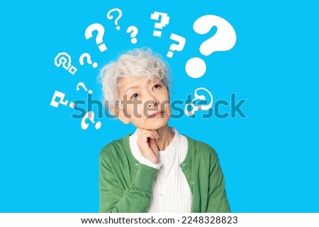 Worried elderly Asian woman with question marks.