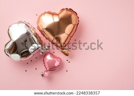 Valentine's Day celebration concept. Top view photo of heart shaped pink silver golden balloons and shiny confetti on isolated light pink background