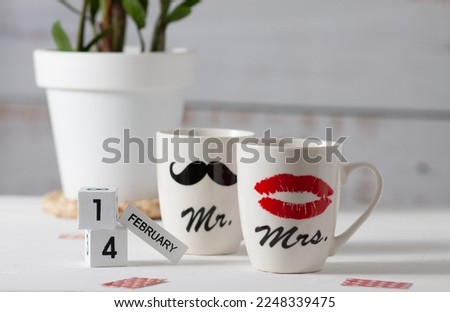 Two white cups that together form a pair. One shows a woman's red lips, and the other a man's black mustache. Good mood for Valentine's Day