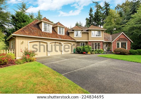 Luxury house exterior with brick trim, tile roof and french windows. House with three car garage
