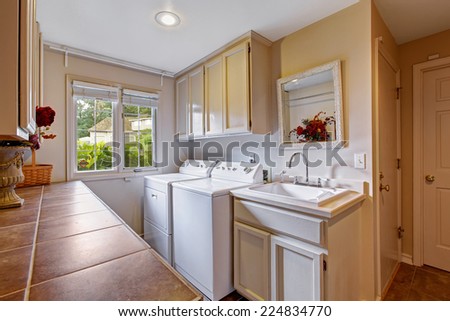 Laundry room with window and standard appliances. Room has cabinets and sink