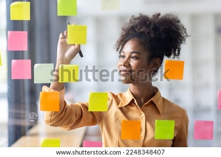 Young Serious african american Creative team use post it notes to share idea sticky note on glass wall. Asian business people design planning and Brainstorming thinking sticky History notes concept.
, Royalty-Free Stock Photo #2248348407