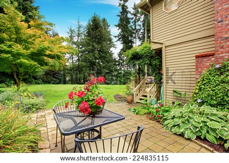 Backyard with tile foor patio area, iron table set decorated with flower pot