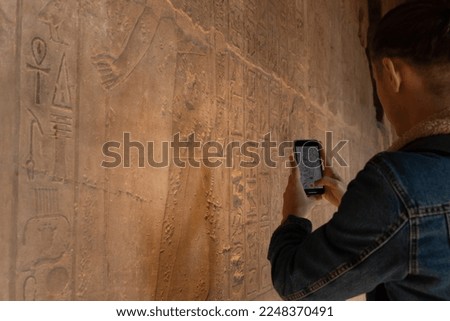 Close up view of young tourist man recording a video for social media to the hieroglyphics inside the egyptian temples