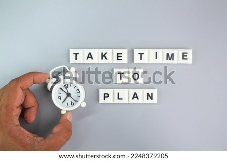 hand holding an alarm clock with alphabet letters of the word Take Time To Plan. concepts take time to plan. planning concept Royalty-Free Stock Photo #2248379205