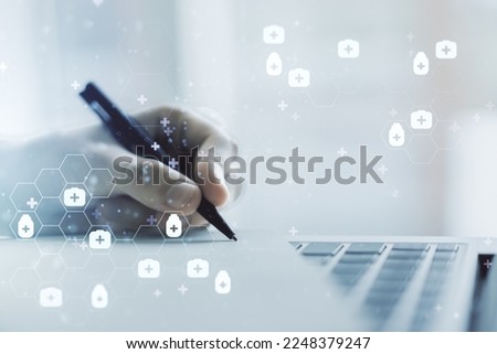 Double exposure of creative abstract medical hologram and hand writing in notebook on background with laptop. Healthcare technolody concept
