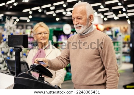 A senior man is paying with credit card on self-service cash register at the supermarket. Royalty-Free Stock Photo #2248385431