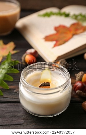 Composition with scented candle and autumn leaves on wooden table