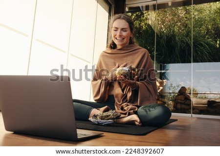 Happy Ayurvedic healer using a singing bowl and sage during a holistic online class. Mature woman performing an alternative purifying ceremony at home. Senior woman taking care of her ageing body. Royalty-Free Stock Photo #2248392607