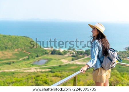Asian woman with backpack solo travel on tropical island mountain peak in summer sunny day. Attractive girl enjoy and fun outdoor lifestyle looking beautiful nature of ocean on beach holiday vacation. Royalty-Free Stock Photo #2248395735