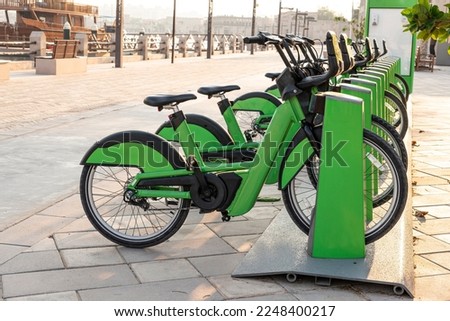 electric bicycles for rent are green in the parking lot in the city center on the street. Eco-friendly mode of transport