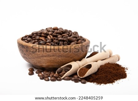 Ground coffee and coffee beans in wooden bowl and spoons isolated on white background.